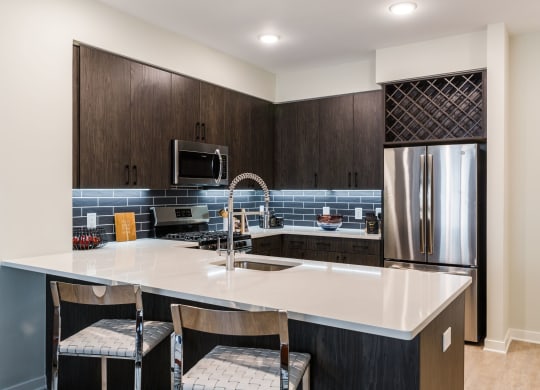 a kitchen with a large island and a stainless steel refrigerator at 100 House Apartments, Jersey City , NJ