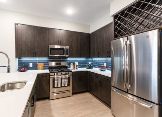 a kitchen with stainless steel appliances and wooden cabinets at 100 House Apartments, Jersey City