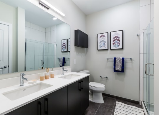 a bathroom with two sinks and a shower and a toilet at 100 House Apartments, New Jersey