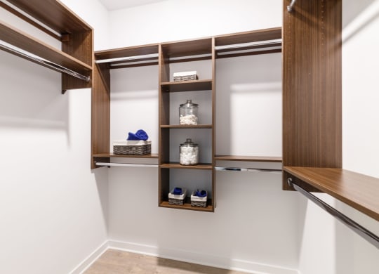 a walk in closet with wooden shelves and white walls at 100 House Apartments, Jersey City , New Jersey