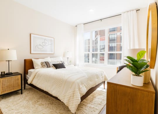 a bedroom with a bed and a large window at One Ten Apartments, New Jersey, 07310