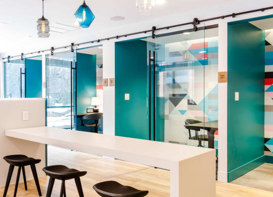 a conference room with a long white table and three black stools at One Ten Apartments, Jersey City , New Jersey