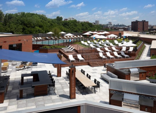 an aerial view of the rooftop lounge area of a hotel with lounge chairs and tables at One Ten Apartments, Jersey City