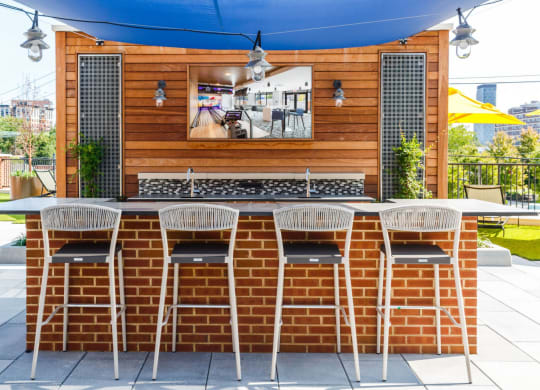 the outdoor bar is under a blue awning and a brick wall with chairs