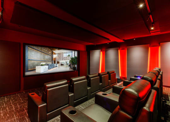 a home theater room with leather seats and a large screen