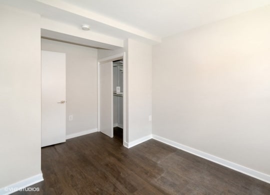 a bedroom with hardwood floors and white walls at Carver and Slowe Apartments, Washington