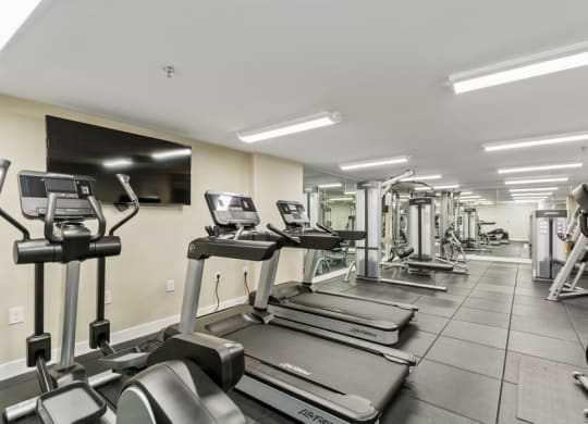 a gym with cardio machines and a flat screen tv at Carver and Slowe Apartments, Washington