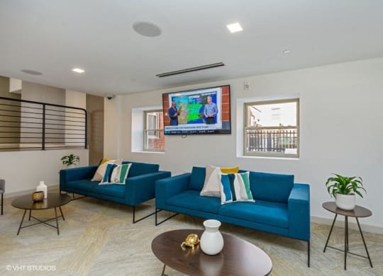 a living room with blue couches and a flat screen tv at Carver and Slowe Apartments, Washington Washington, DC