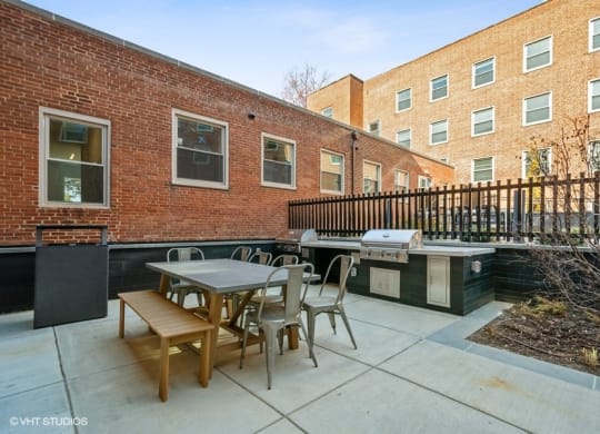 a patio with a table and chairs and a grill in front of a brick building at Carver and Slowe Apartments, Washington, DC