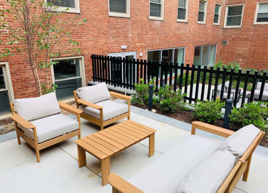 a patio with wooden furniture and a brick building in the background at Carver and Slowe Apartments, Washington, DC