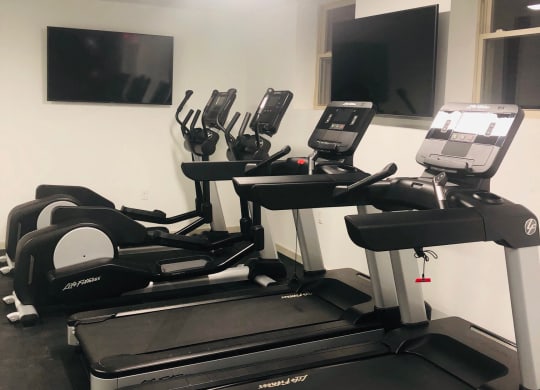 a gym with treadmills and a flat screen tv at Carver and Slowe Apartments, Washington, DC