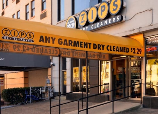 a store front of a building with a yellow sign that reads any garment dry cleaned