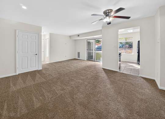 A spacious room with a carpeted floor and a ceiling fan.