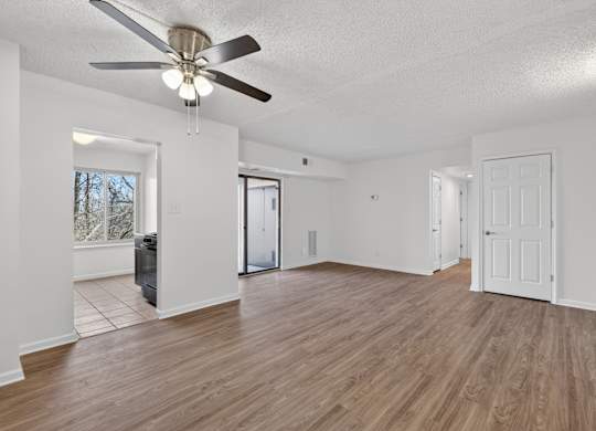 A room with a ceiling fan and wooden flooring.