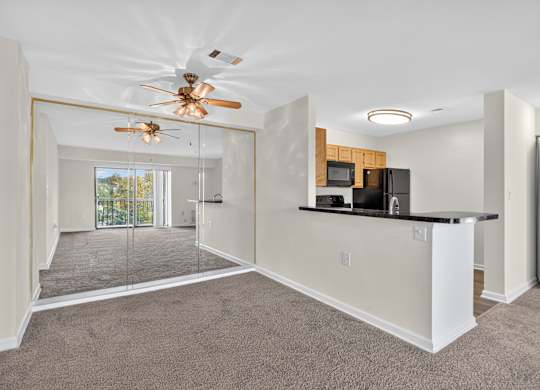 A spacious living room with a ceiling fan and a kitchen.