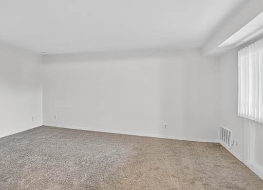 A large, empty room with carpeted floor and white walls.