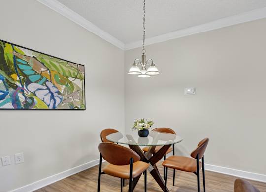 A dining room with a table set for two and a painting on the wall.