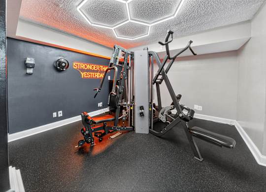 A gym room with a rowing machine and a weight machine.