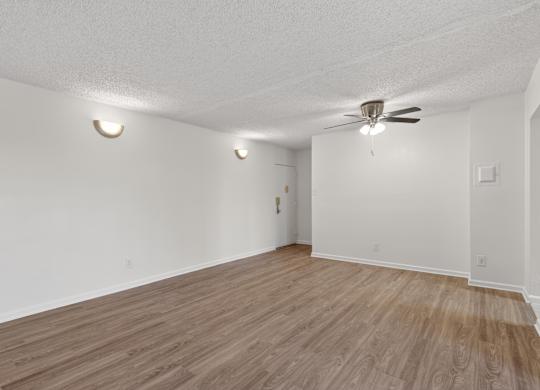 Empty room with wooden floor and ceiling fan.