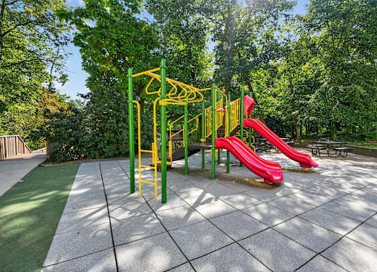 A playground with a red slide and a yellow structure.