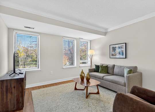 A living room with a grey couch, a wooden coffee table, and a brown armchair.