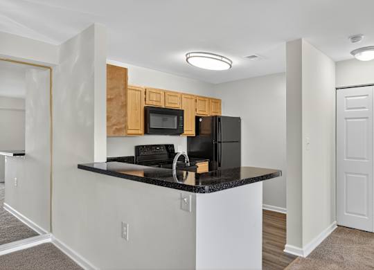 A kitchen with a black counter top and white cabinets.