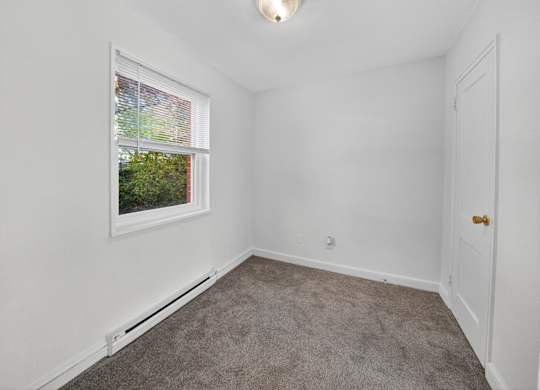 A room with a window and a carpeted floor.