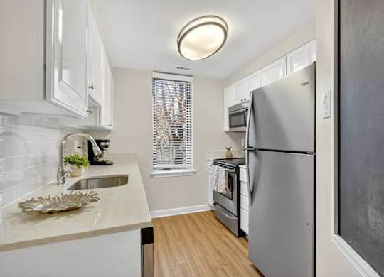 A kitchen with a refrigerator, sink, and window.