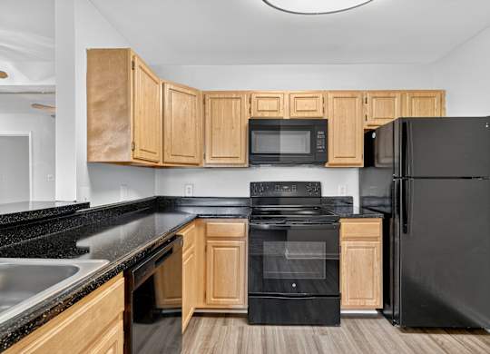 A kitchen with black appliances and wooden cabinets.