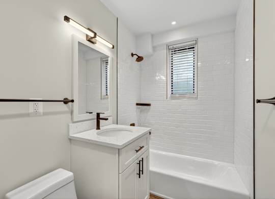 A white bathroom with a toilet, sink, and bathtub.