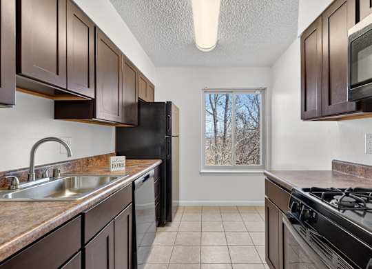 A kitchen with brown cabinets and black appliances.