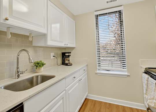 A kitchen with white cabinets and a stainless steel sink.