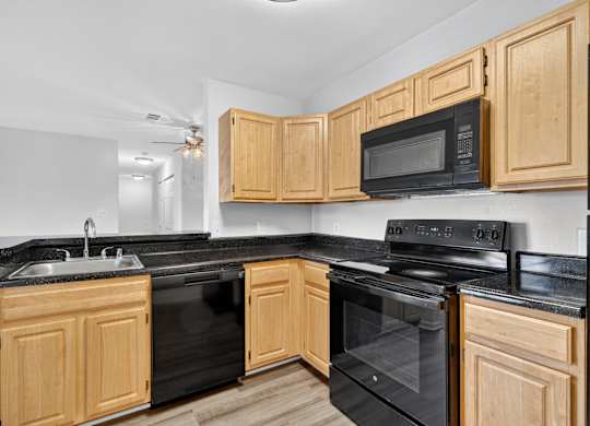 A kitchen with black appliances and wooden cabinets.