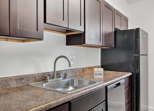 A kitchen with brown cabinets and a black refrigerator.