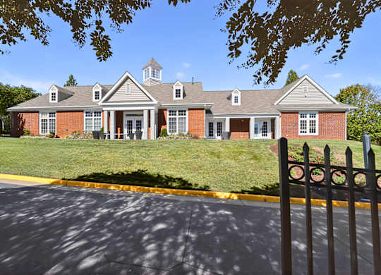 A red brick building with a black fence in front.