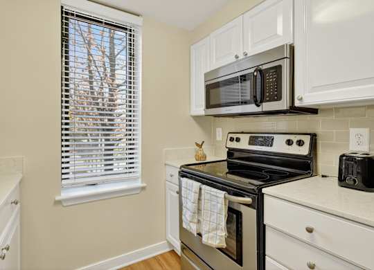 A kitchen with a stove, microwave, and oven.