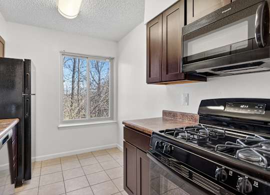 A kitchen with black appliances and brown cabinets.