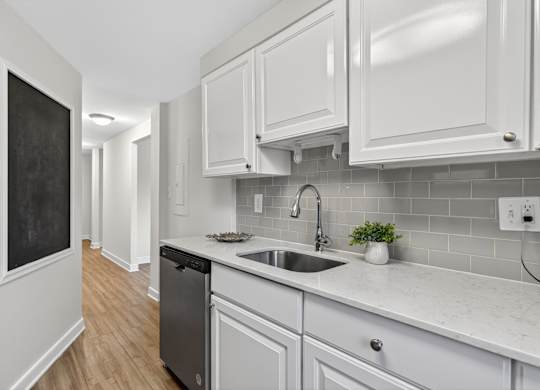 A kitchen with white cabinets and a blackboard on the wall.