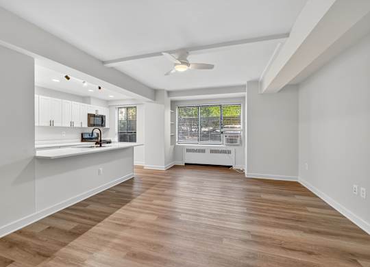 A spacious room with wooden flooring and a ceiling fan.
