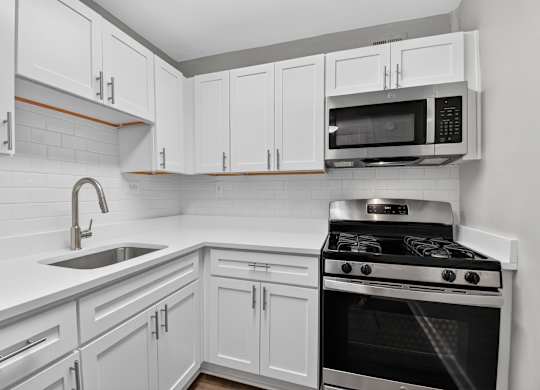 A kitchen with white cabinets and a black stove.