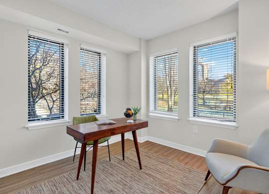 A room with a table, chairs and windows.