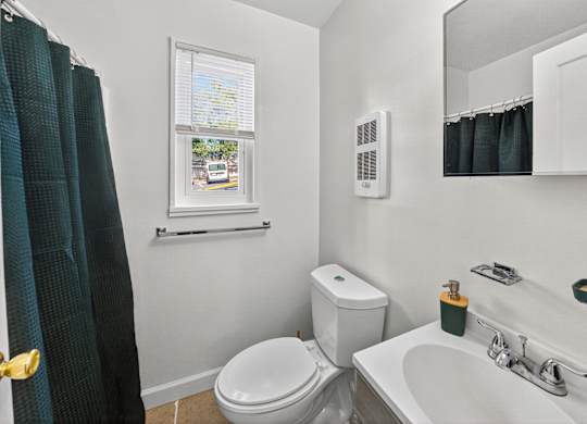 A bathroom with a toilet, sink, and window.