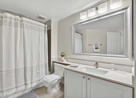 A white bathroom with a toilet, sink, and shower curtain.