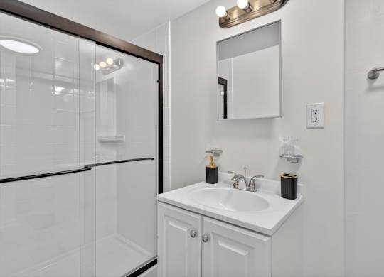 A white bathroom with a sink and mirror.