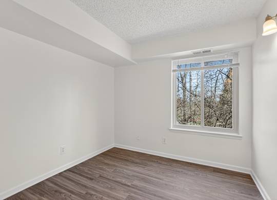 A room with a window and wooden flooring.