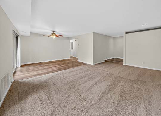 A room with a carpeted floor and a ceiling fan.