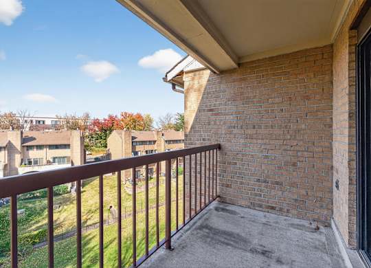 A balcony with a brick wall and a metal railing.