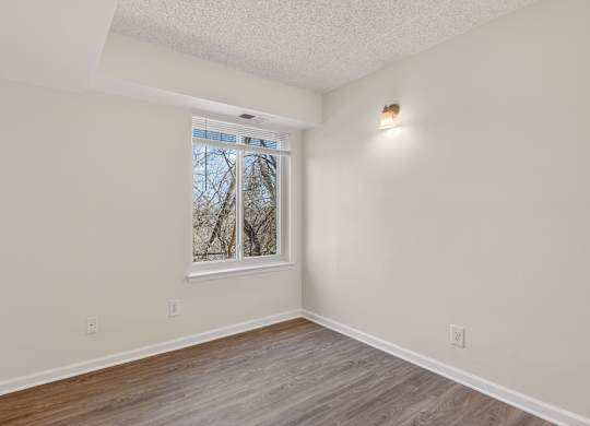 A room with a window and a wooden floor.