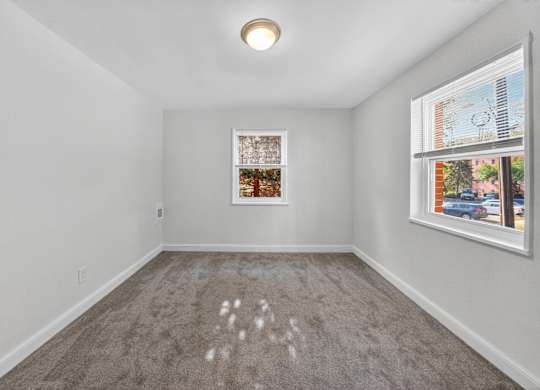 A room with a grey carpet and a picture frame on the wall.