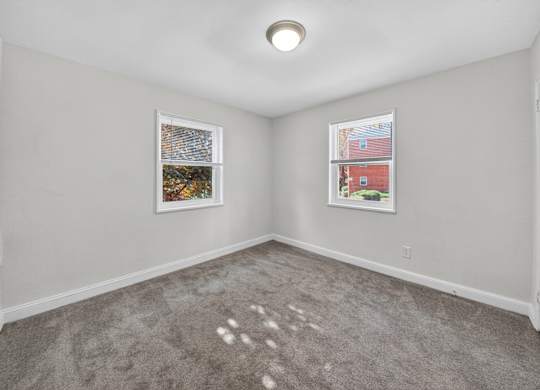 A room with a grey carpet and two pictures on the wall.